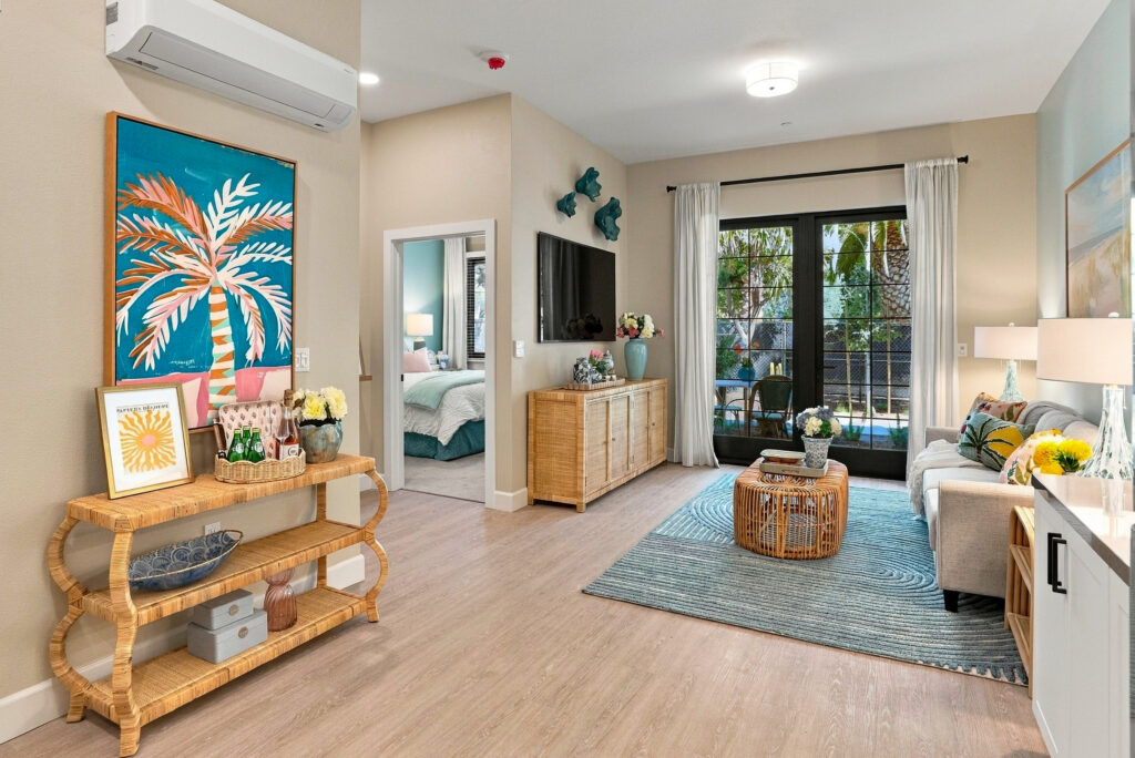 Living space with a sofa and TV, entrance to a bedroom, and a full glass door out to a terrace