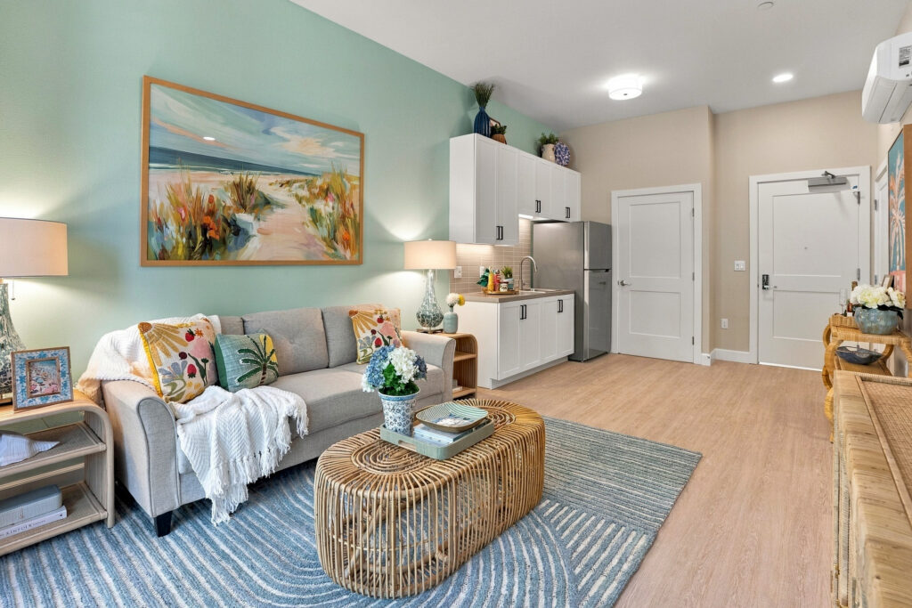 Living space with bright pastel decor, including a sofa and galley kitchen