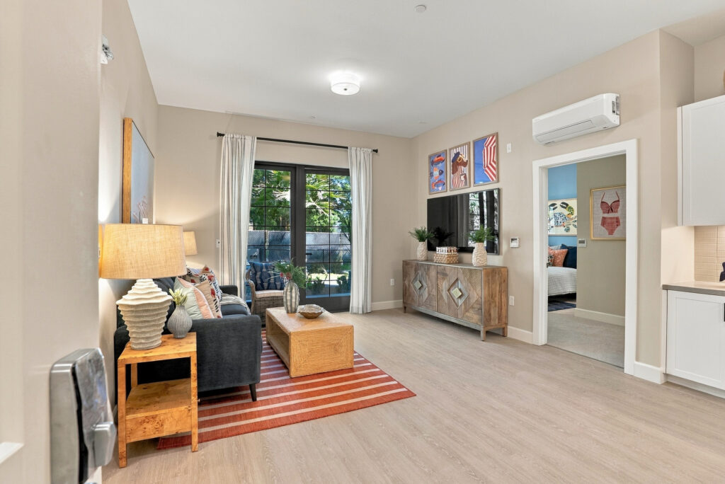 Living space with a sofa and TV, entrance to a bedroom, and a full glass door out to a terrace