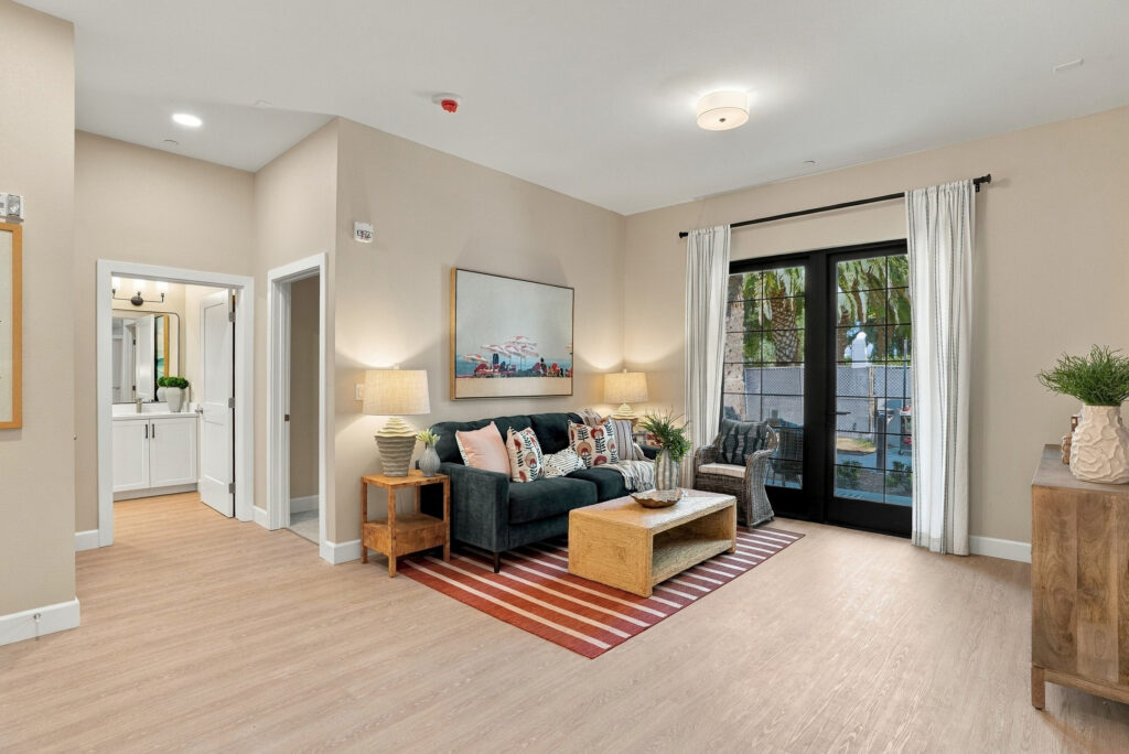 View of living space with blue and orange decor, glass door out to terrace, and entrances to the bedroom and bathroom.