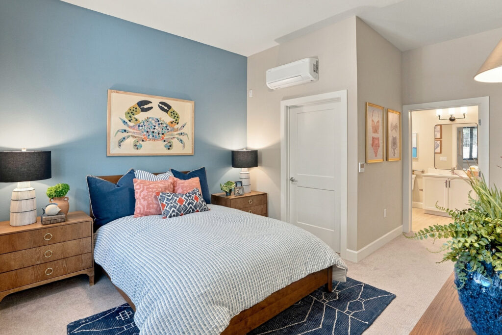 Bedroom with blue decor, end tables with lamps, and entrance to the bathroom.