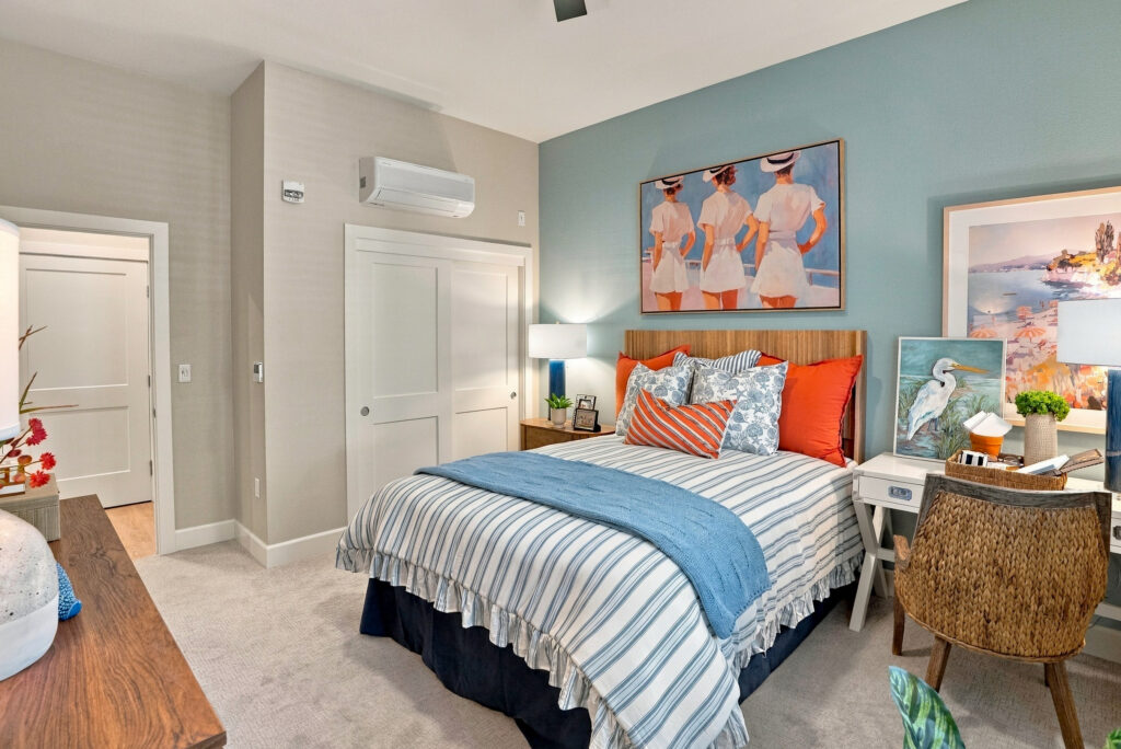 Bedroom space with blue and orange decor, with a desk and chair next to the bed