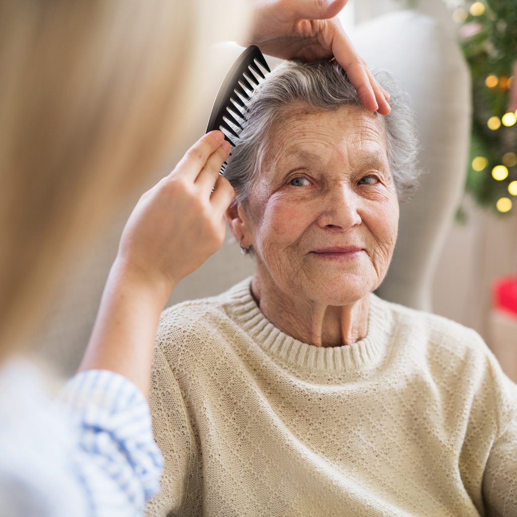 a resident smiles as a hair dresser styles her hair